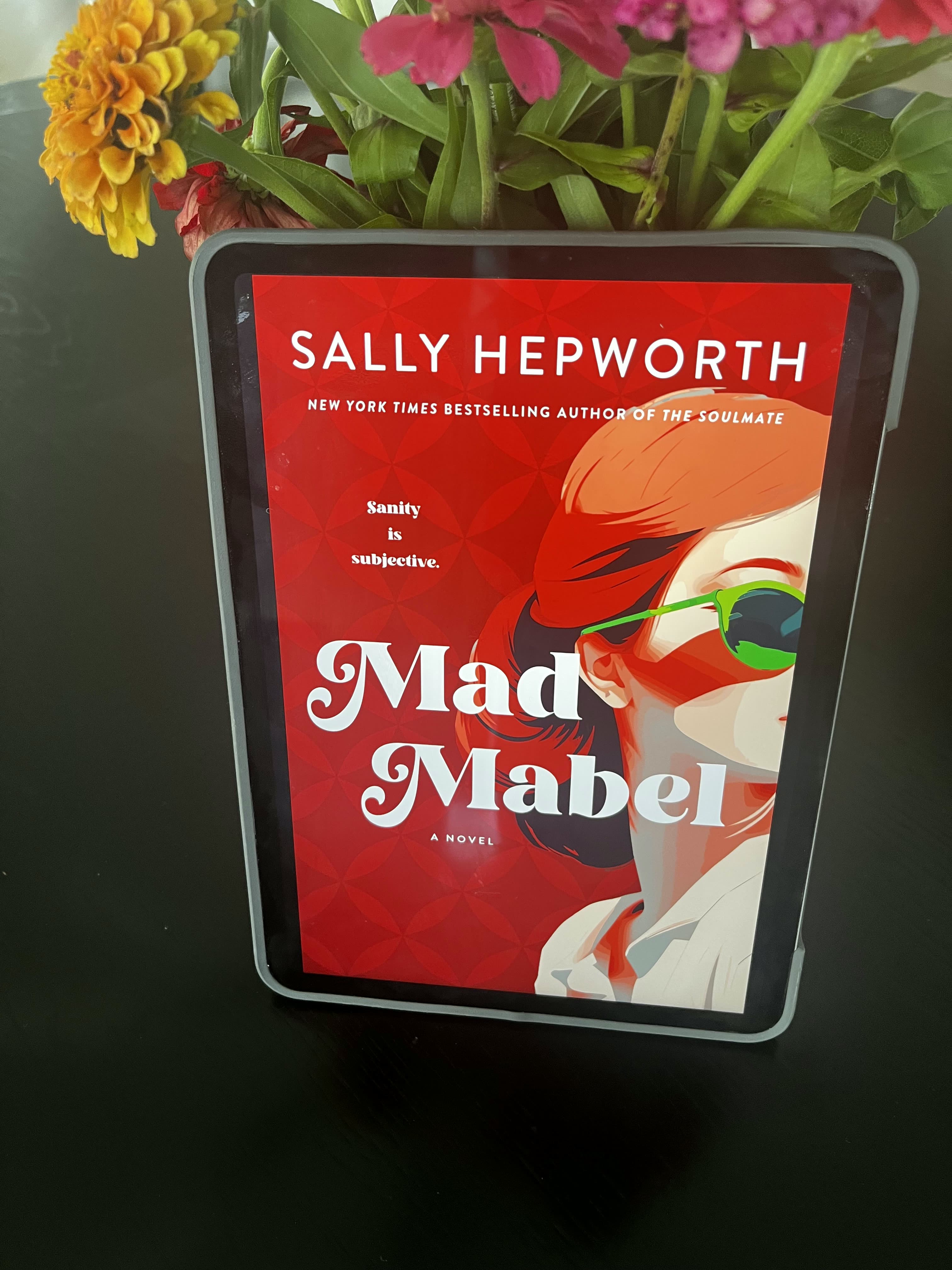 Mad Mabel displayed on an e-reader beside fresh flowers